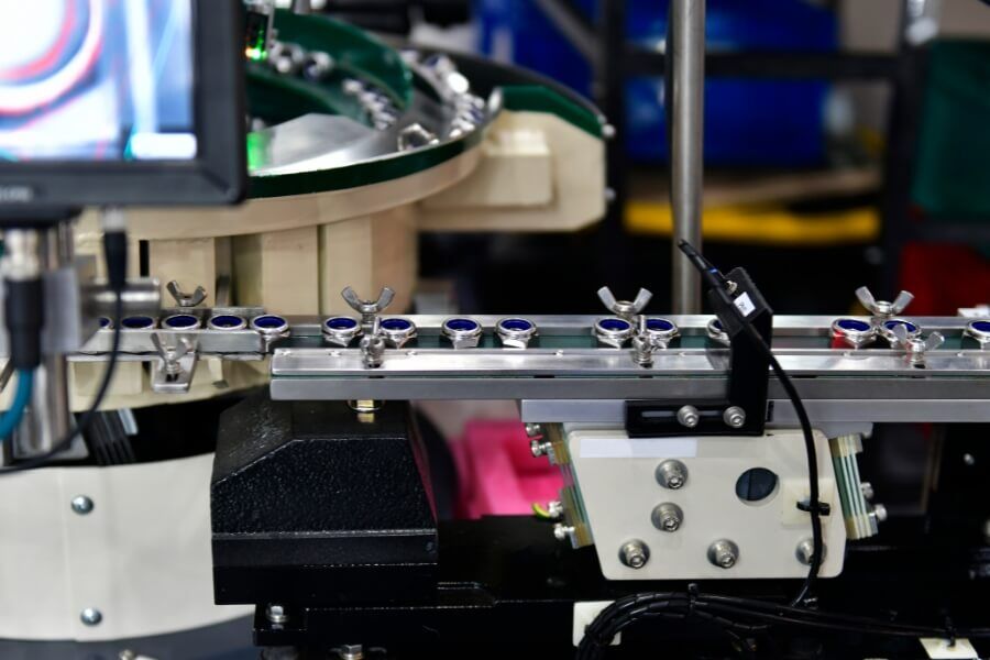 고속 컨베이어 위를 지나가는 제품을 향해 여러 각도에서 조명이 비춰지고, 비전 카메라가 촬영하여 모니터에 OK/NG 판정을 띄우는 검사 라인 전경